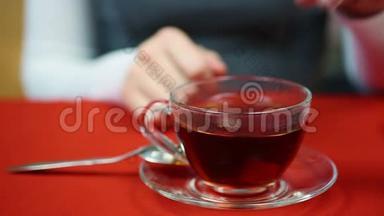 女人在杯子里搅拌精制的糖，喝热红茶，和朋友见面